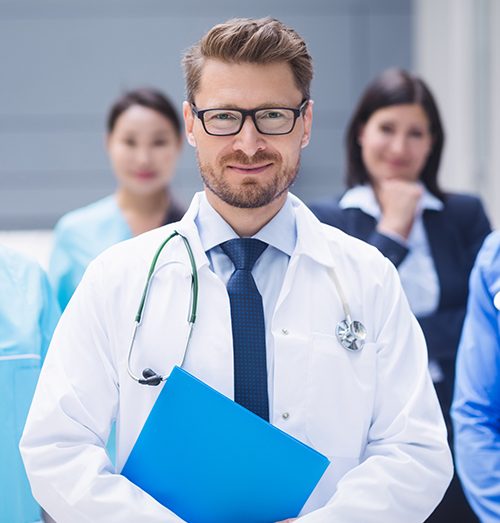 Male doctor holding a folder with a medical team standing behind him